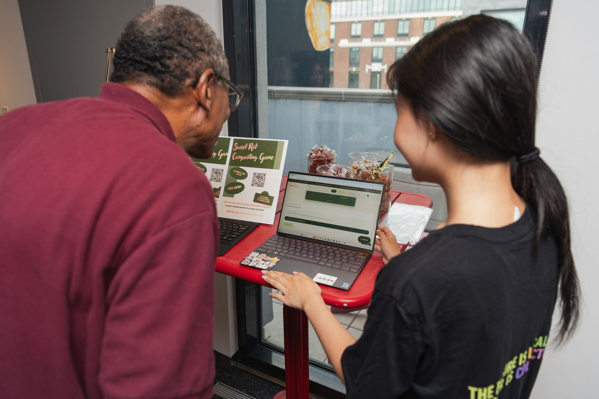A neighbor and an Operator playing the Sweet Rot composting game on a laptop